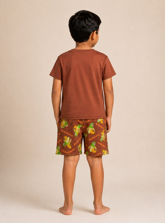 Back view of a boy wearing Chillpjs Bananini cotton shorts night suit with a brown t-shirt and banana print shorts.