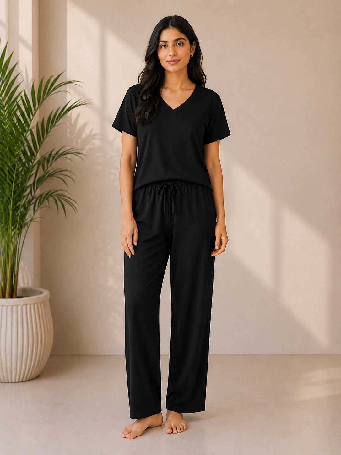 A woman wearing a Chillpjs black cotton jersey V-neck lounge set with a relaxed fit and elastic drawstring waistband.