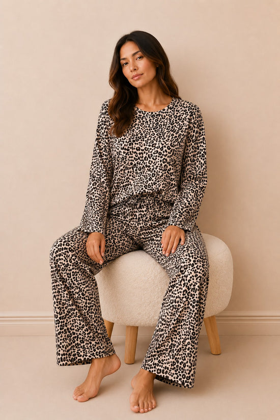 Chillpjs cheetah print two-piece lounge set with full sleeves and straight-fit trousers on a woman sitting on a stool