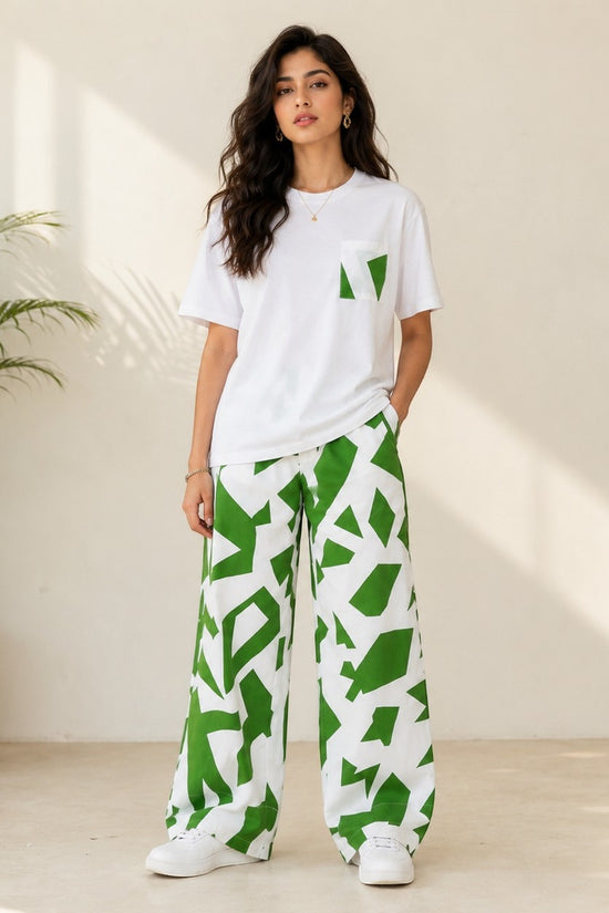 Model wearing Chillpjs Urban Pop lounge set with white t-shirt and green abstract print wide-leg trousers.