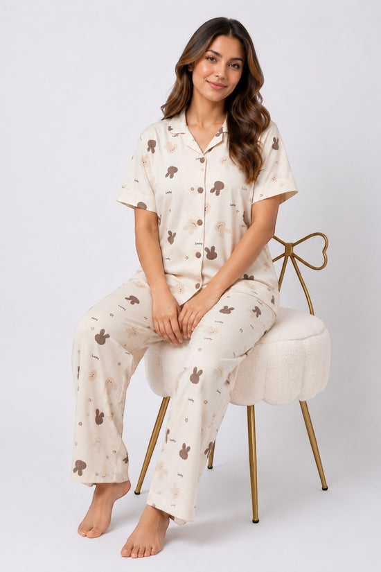 Woman wearing Chillpjs Lucky Bunny pajama set in sandstone cream popcorn crinkle fabric with brown bunny motifs.