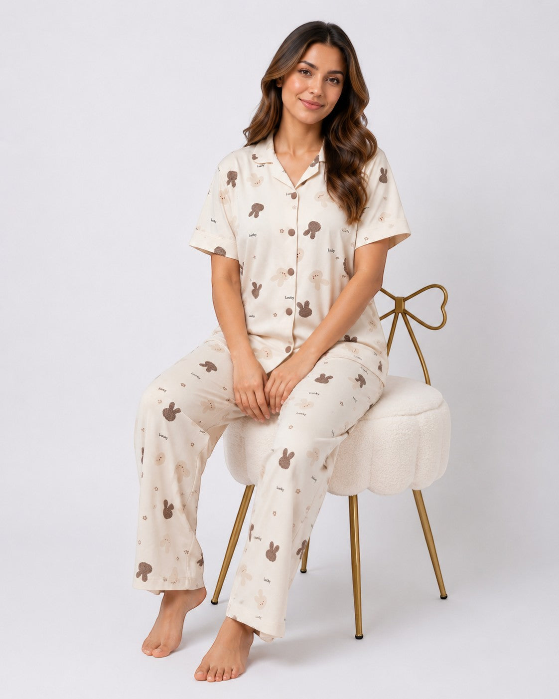 Woman wearing Chillpjs Lucky Bunny pajama set in sandstone cream popcorn crinkle fabric with brown bunny motifs.