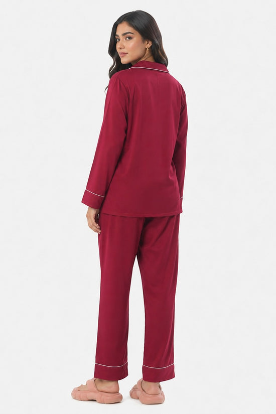Model wearing a maroon Chillpjs satin silk pajama set with white piping, viewed from the back against a white background