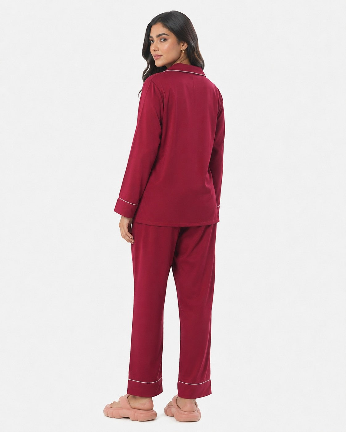 Model wearing a maroon Chillpjs satin silk pajama set with white piping, viewed from the back against a white background