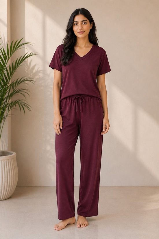 A woman wearing a Chillpjs midnight burgundy cotton jersey V-neck lounge set with a relaxed fit and elastic waistband.