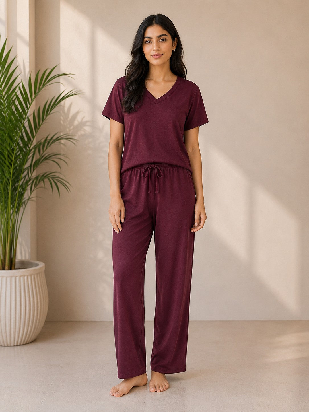 A woman wearing a Chillpjs midnight burgundy cotton jersey V-neck lounge set with a relaxed fit and elastic waistband.