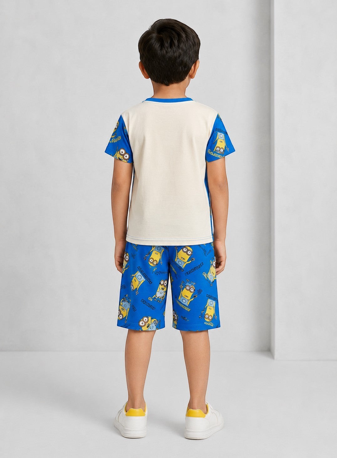 Back view of a boy wearing a Chillpjs Minions cotton shorts night suit with a blue and cream graphic print.