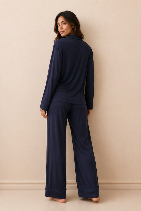 Model wearing a Chillpjs navy blue linen pajama set with long sleeves and wide-leg trousers, viewed from the back.