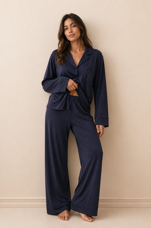 A woman wearing a Chillpjs navy blue soft linen pajama set with a long-sleeve button-down shirt and wide-leg trousers.