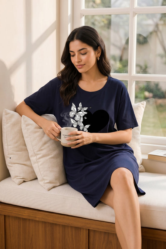 Chillpjs navy oversized t-shirt dress with a black heart and white butterfly graphic worn by a woman holding a mug
