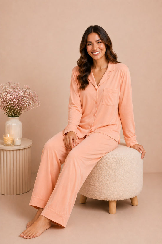 A woman wearing a Chillpjs peach soft linen pajama set with a notch lapel collar and wide-leg trousers.