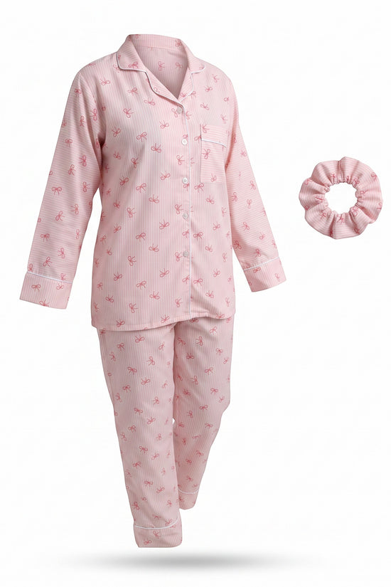Chillpjs pink pajama set with bow print, featuring a button-up long-sleeve top, matching pants, and a hair scrunchie.