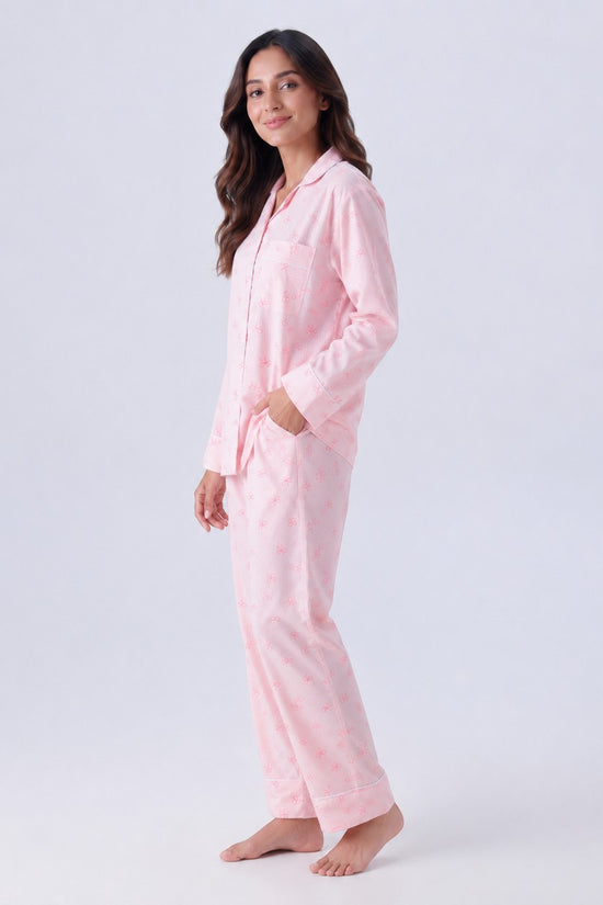 Chillpjs pink pajama set with bow pattern, featuring a long-sleeve button-down top and matching trousers on a model.