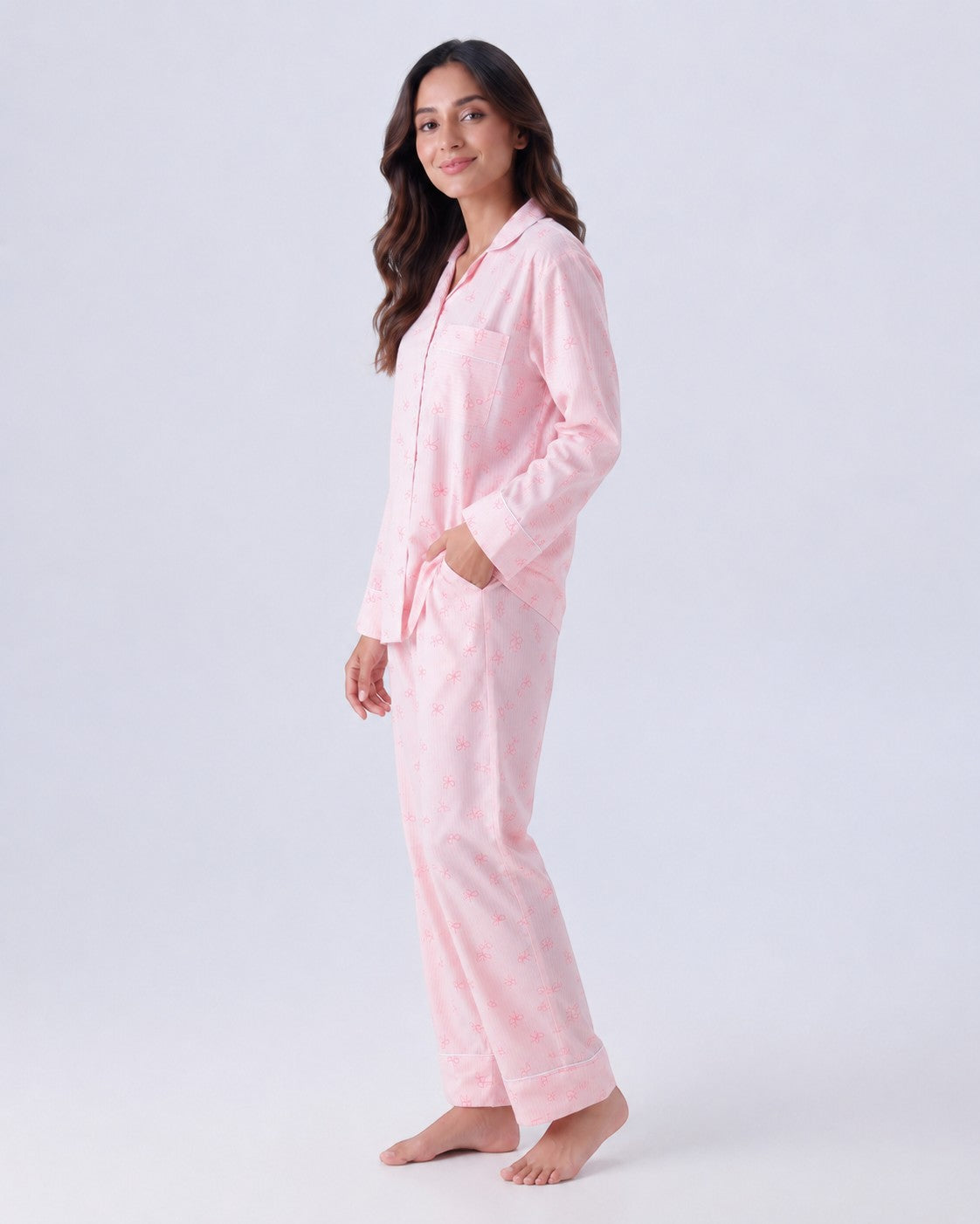 Chillpjs pink pajama set with bow pattern, featuring a long-sleeve button-down top and matching trousers on a model.