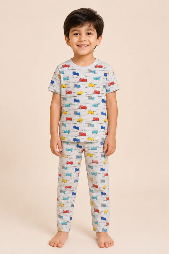 Chillpjs Road Trip Rally pajama set on a smiling boy, featuring a heather gray cotton top and pants with car print.