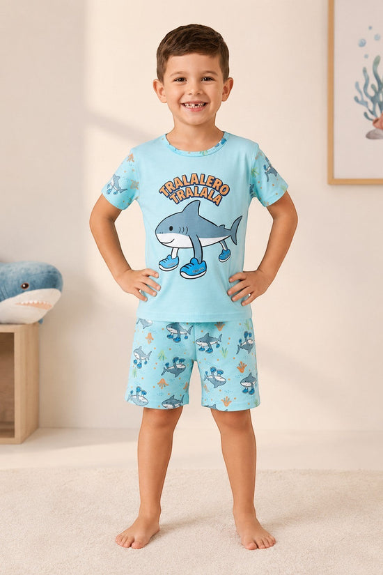 Chillpjs boy wearing a light blue shark-themed cotton pajama set with a graphic t-shirt and matching printed shorts.