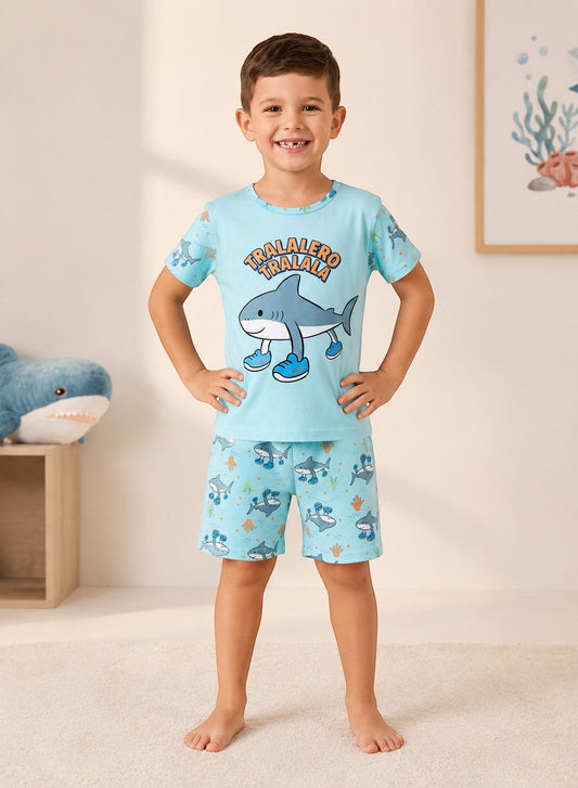 Chillpjs boy wearing a light blue shark-themed cotton pajama set with a graphic t-shirt and matching printed shorts.
