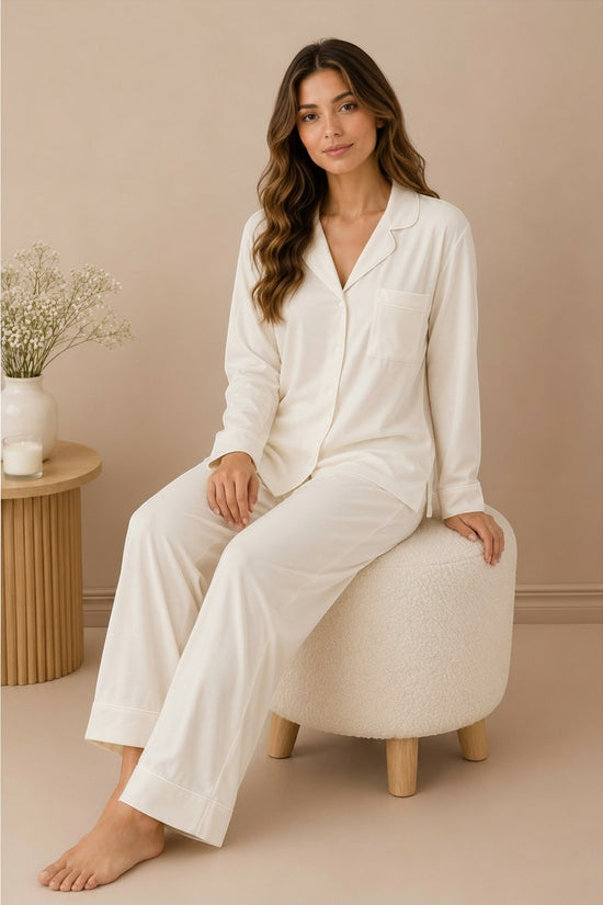Chillpjs white linen pajama set with long sleeves and notch lapel worn by a woman sitting on a textured stool