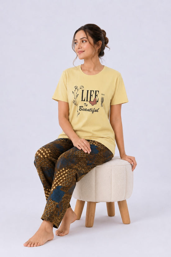 Chillpjs yellow graphic tee and geometric print lounge pants set worn by a woman sitting on a stool.