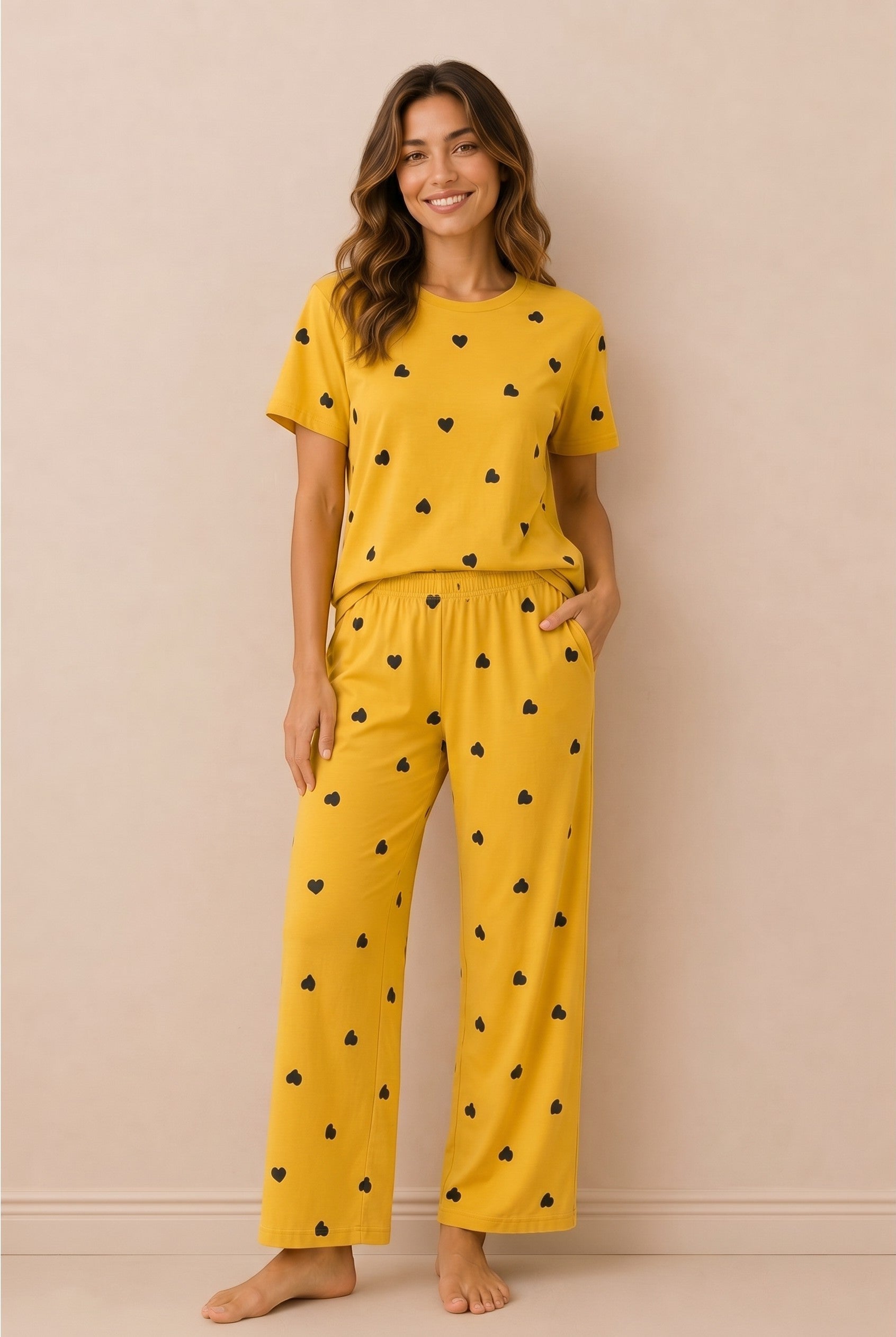 Model wearing Chillpjs marigold yellow pajama set with black heart print, short-sleeve top and relaxed trousers.