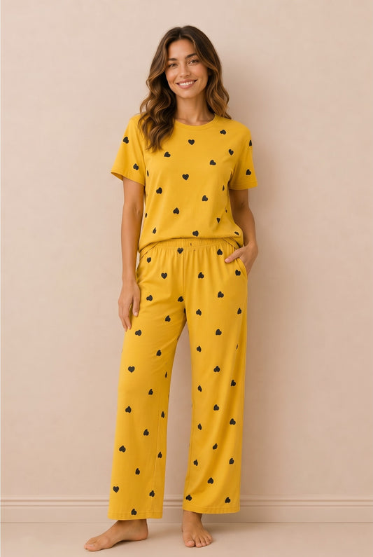 Model wearing Chillpjs marigold yellow pajama set with black heart print, short-sleeve top and relaxed trousers.