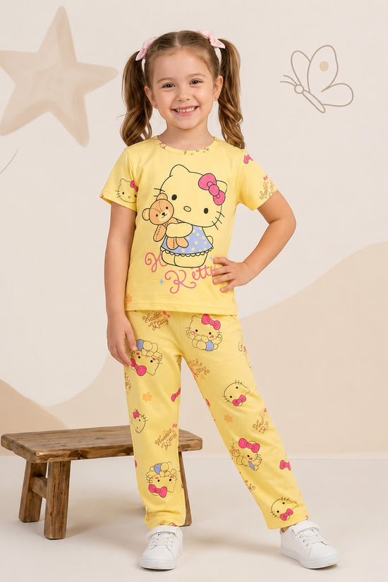 Young girl smiling in a Chillpjs yellow Hello Kitty cotton pajama set with short sleeves and matching trousers.
